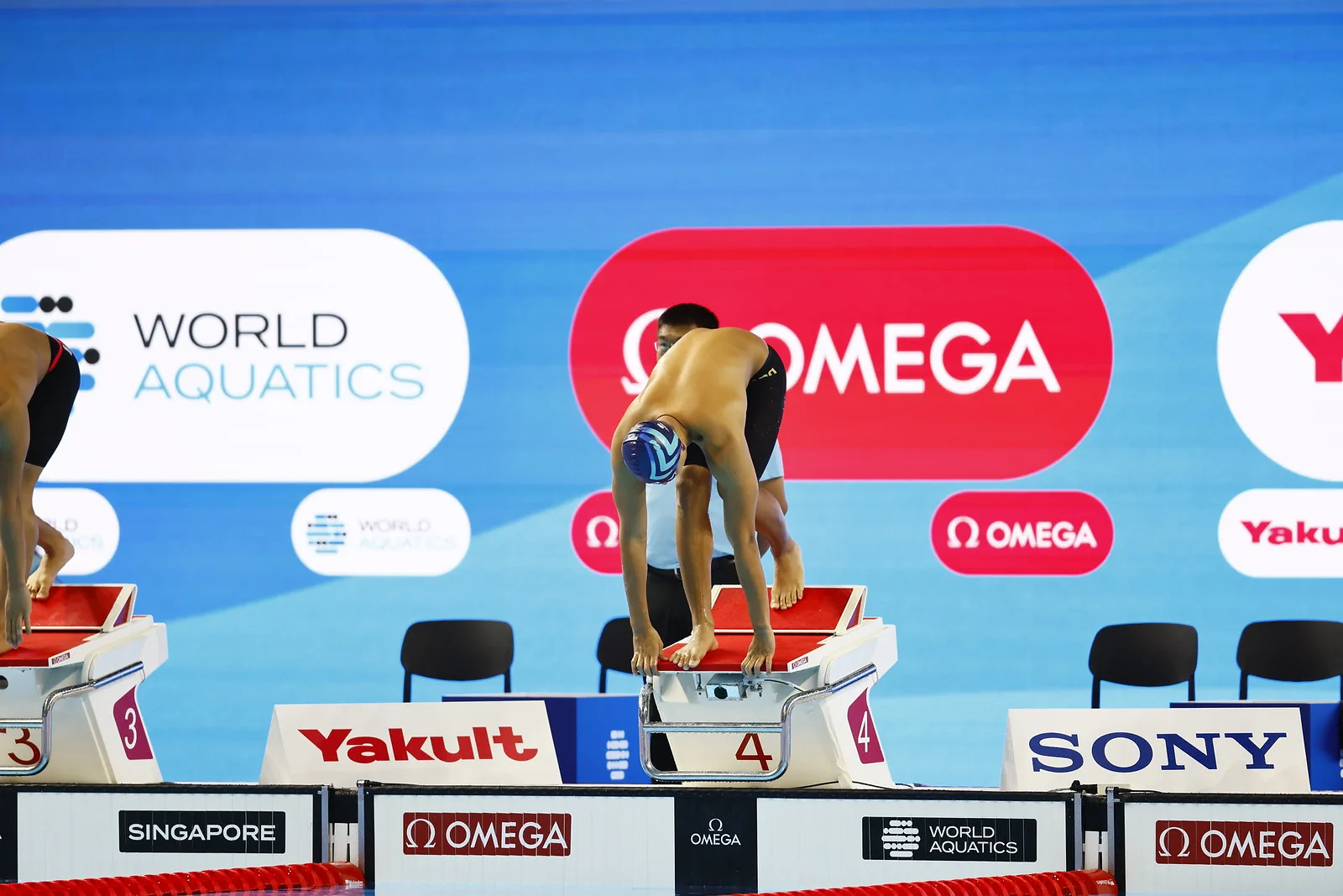 A swimmer set in the take your marks position on a starting block, moments before the start.