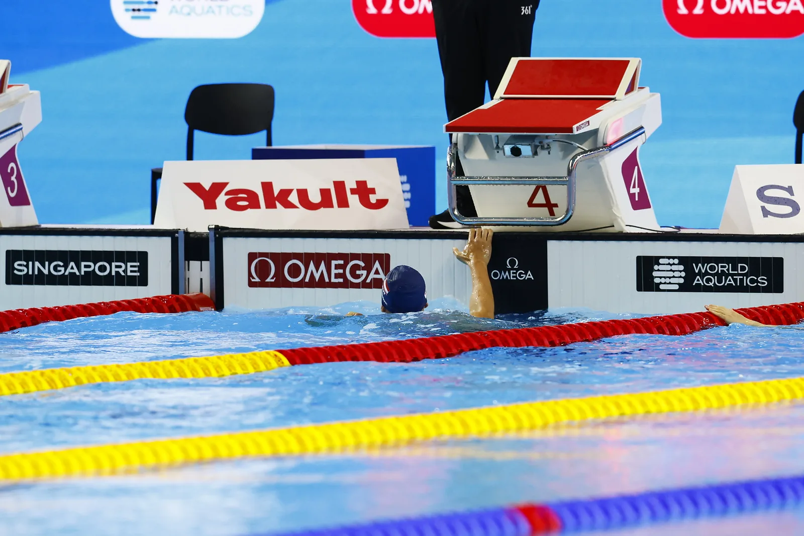 A swimmer touching the finish wall at the end of a race.