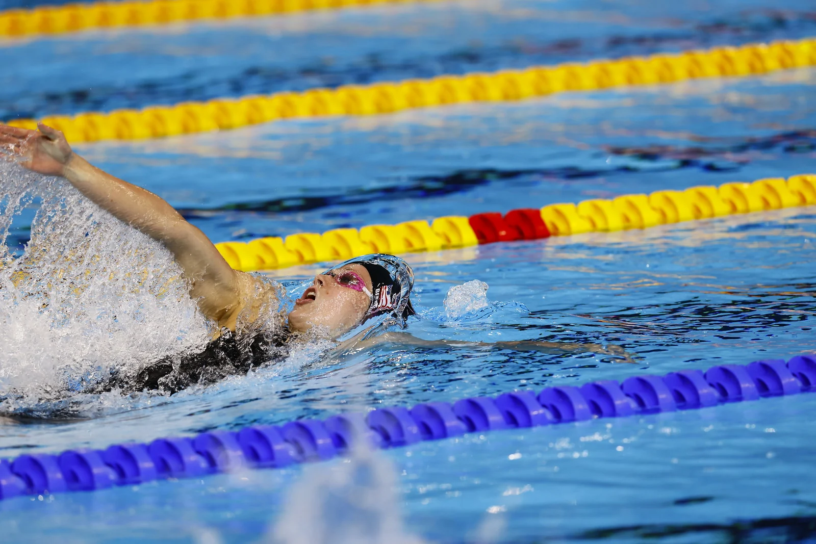 Katharine Berkoff swimming backstroke at high speed between competition lane lines